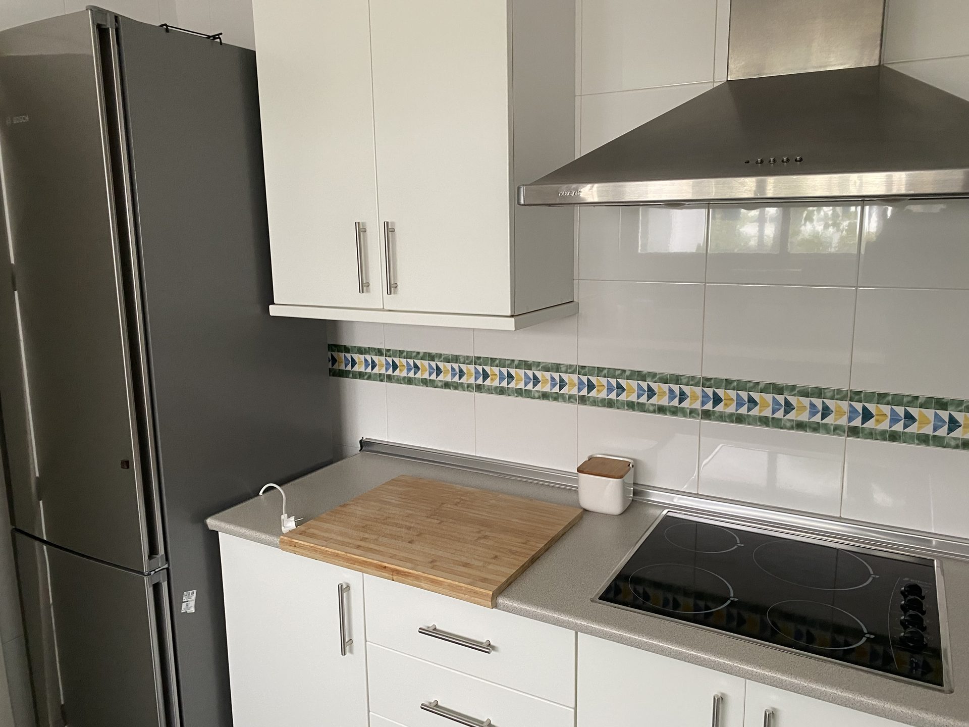 Kochbereich der Küche mit Ceranfeld, Dunstabzug und Kühlschrank