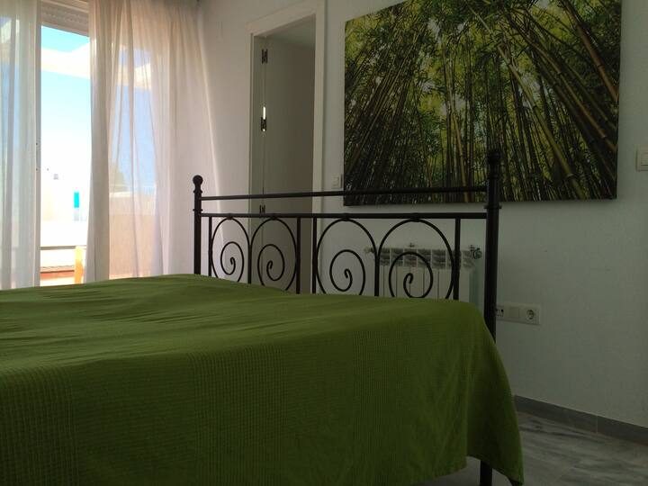Schlafzimmer mit Metallbett und offener Terrassentür