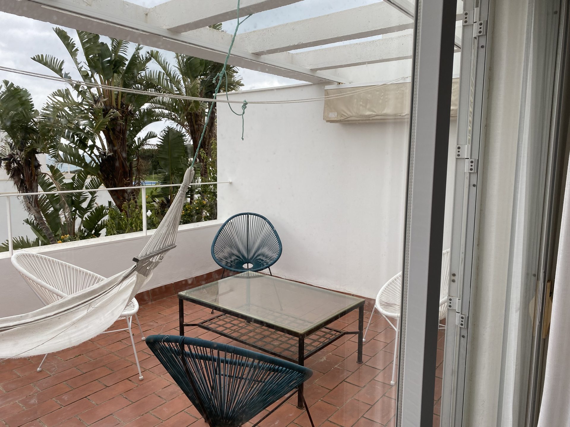 Überdachte Veranda mit Hängematte und Sitzgruppe